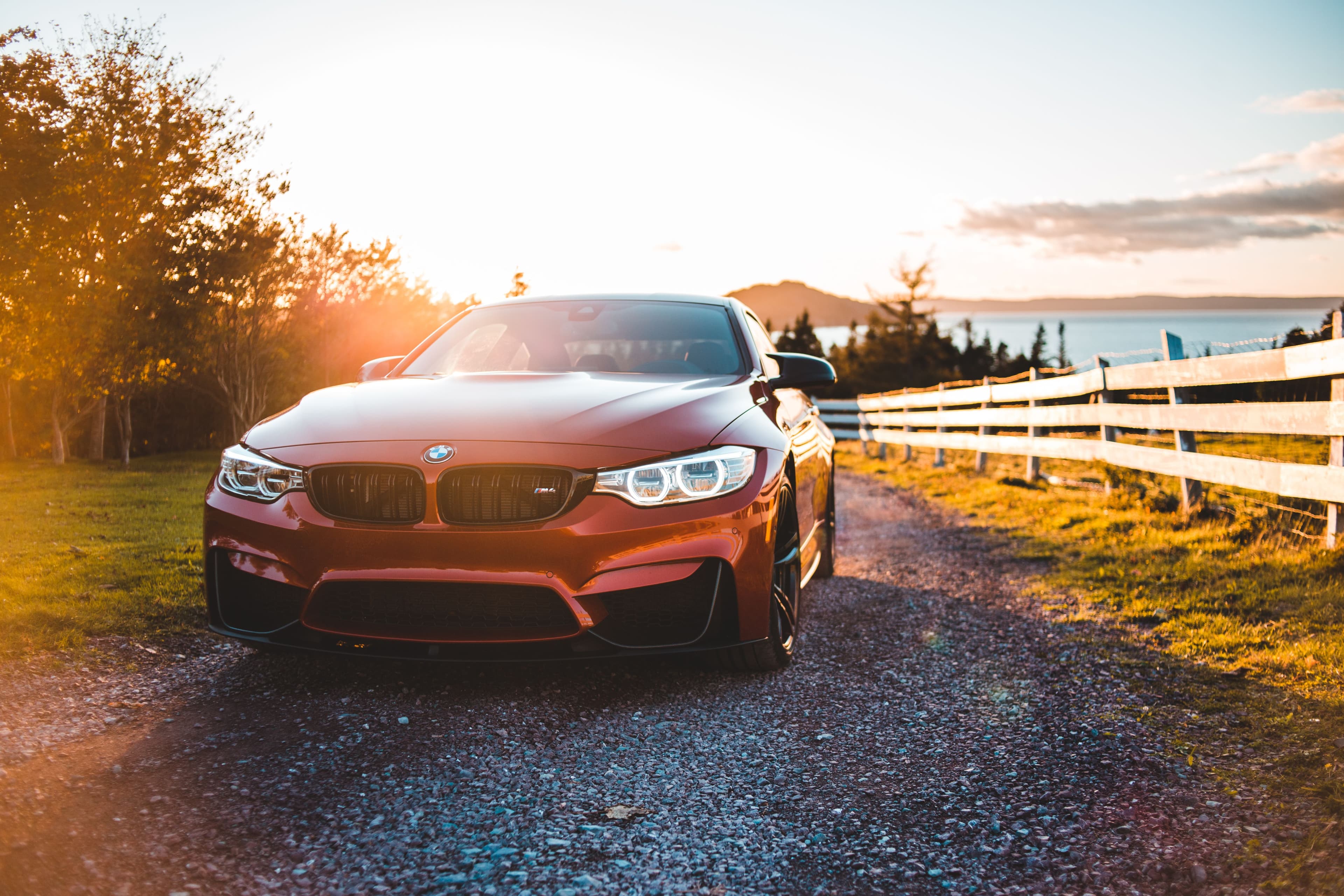 A red car on a country road at sunset